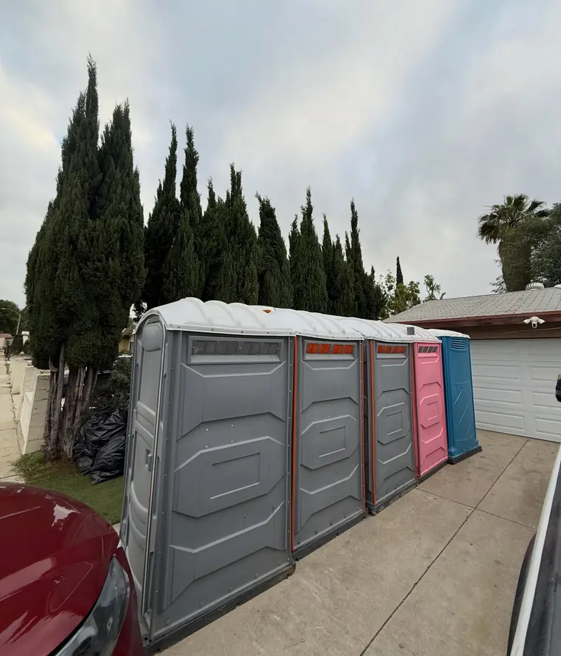 Row of five portable toilets delivered side by side on a residential concrete driveway