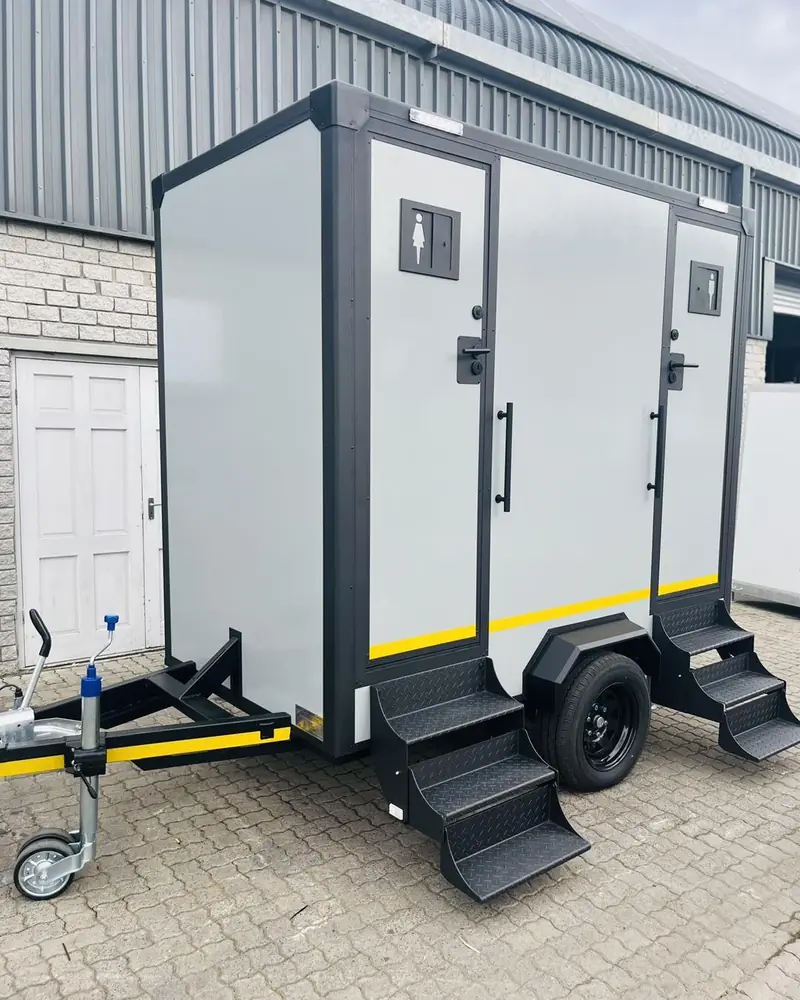 Two-stall restroom trailer with separate entry doors and fold-down steps